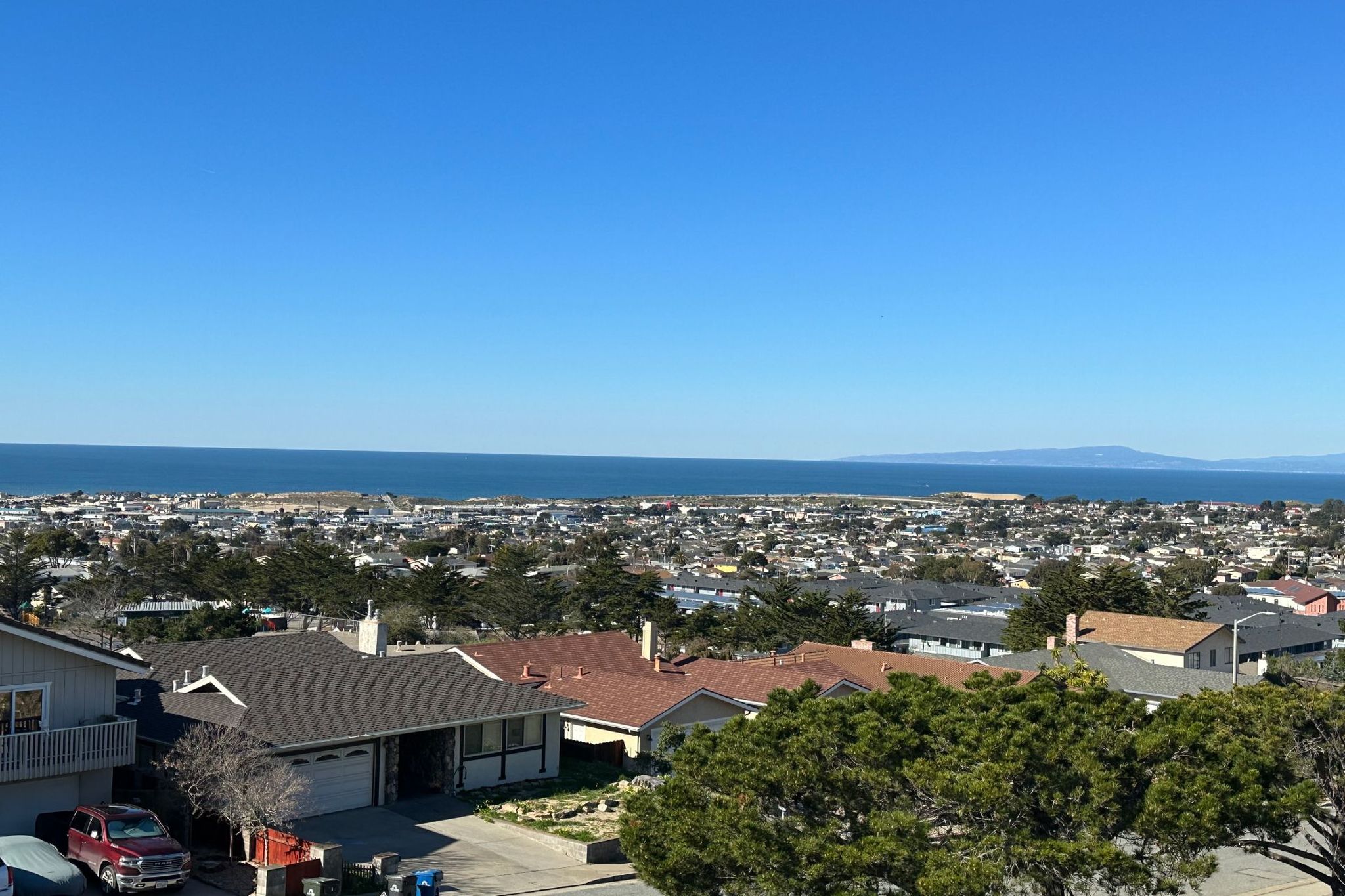 View from the Seaside hills over rooftops and cypress trees to Monterey Bay on a clear day
