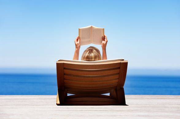 Young woman lying in sun reading book