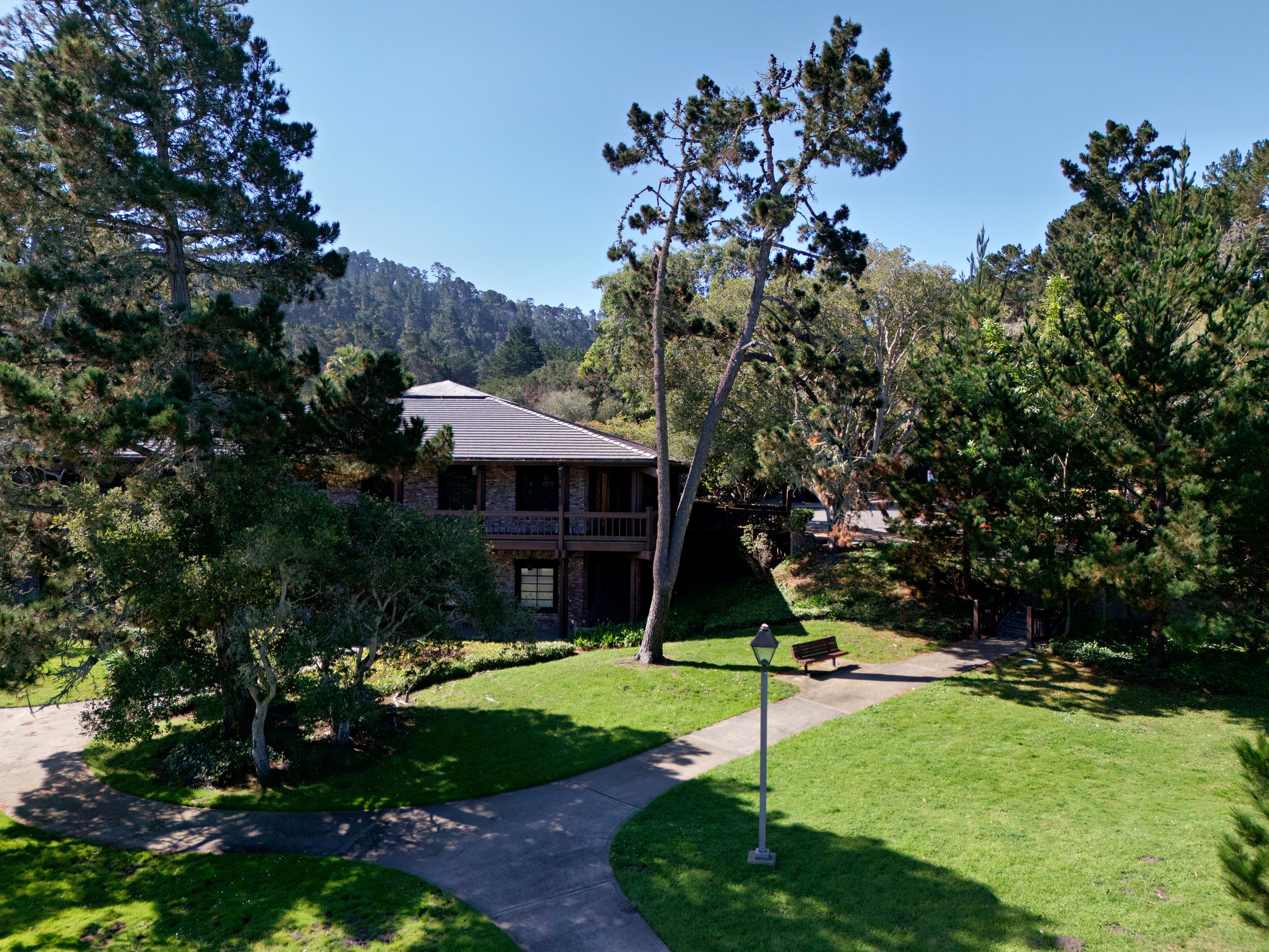 1400 Munras Avenue seen from the landscaped grounds, surrounded by Monterey pines and cypress