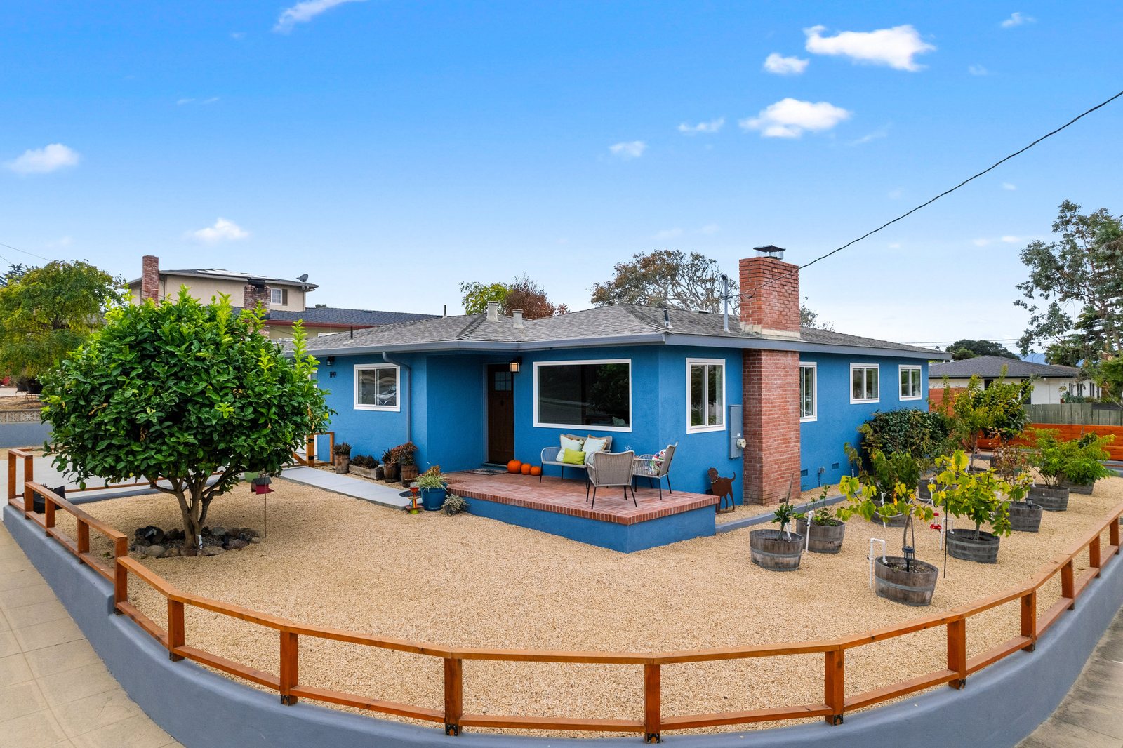 Blue single-level home with a red brick chimney and a fenced, landscaped front yard at 1149 Modoc Street in Seaside