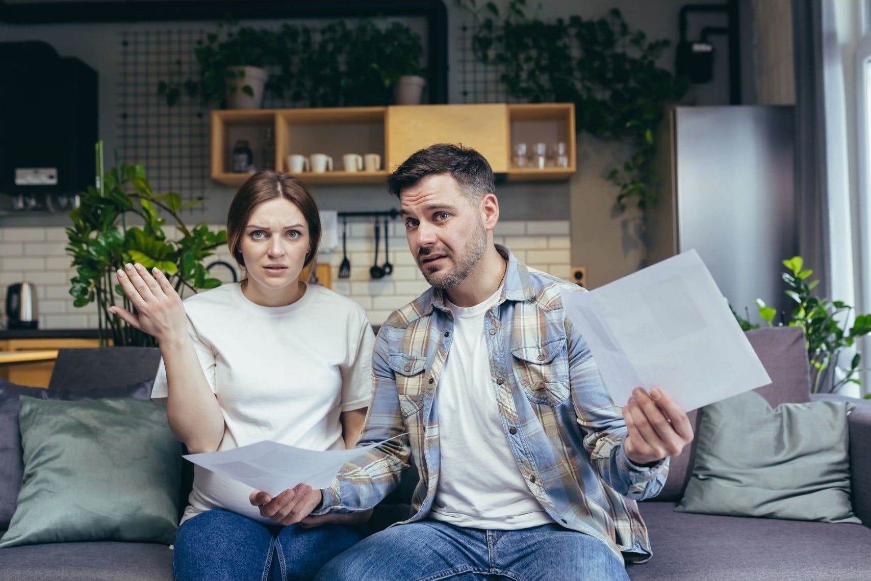 Confused couple sitting on their couch holding contract paperwork after losing an offer on a home in Ventura County — Betty Fernandez, REALTOR®/Broker-Associate with eXp Realty, explains why offers get rejected beyond price.