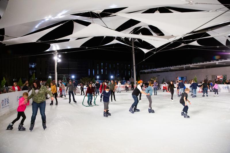 Families ice skating under twinkling lights at Merry Main Street in Downtown Mesa.