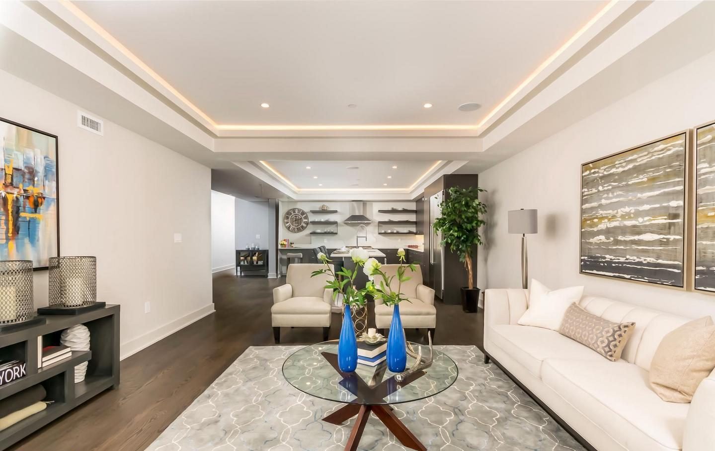 Photograph - Sleek modern living room with a sofa, two armchairs, a glass table, and two blue vases