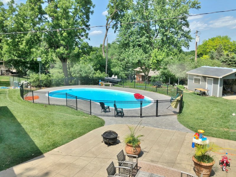 Backyard patio and pool area with spring greenery and planters in Omaha