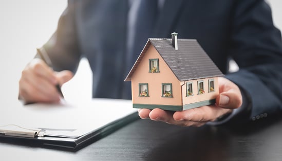 Real estate agent is holding a house model. Buy, loan for a house