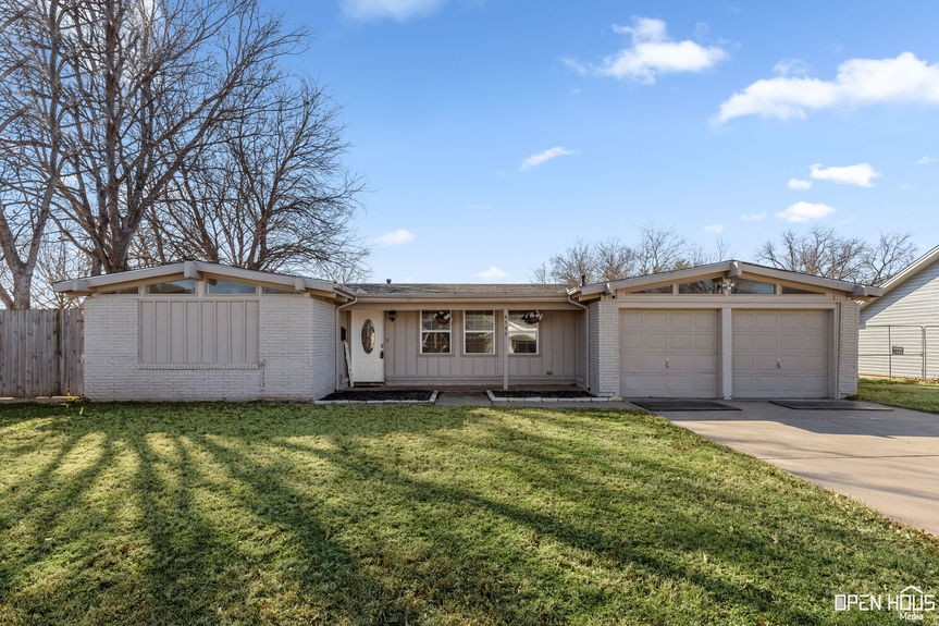 Exterior view of 4103 Berwick Dr showing a mid-century modern home with a double garage and a white painted brick facade.
