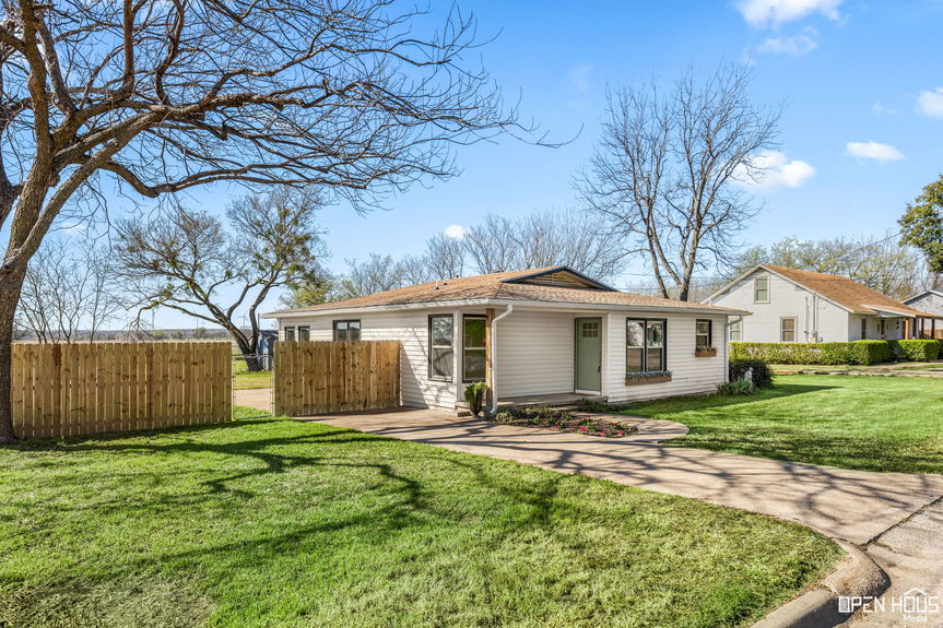Angled view of a cream-colored single-story house with a wooden privacy fence in Jacksboro, Texas.