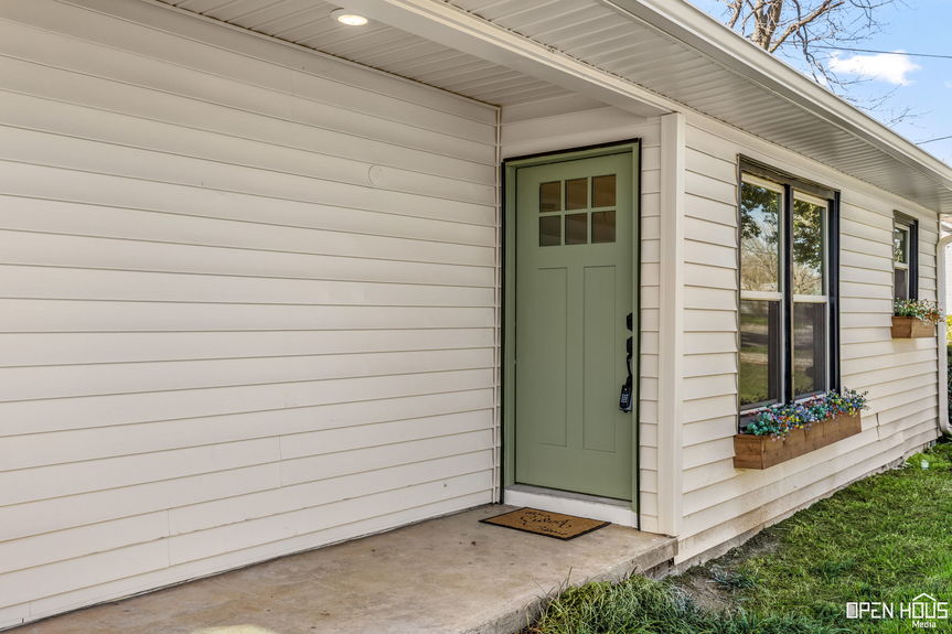 Close-up of the house entrance with a sage green door and window flower box in Jacksboro, TX.