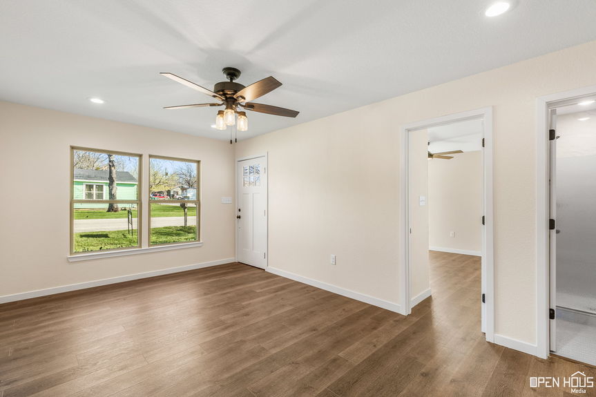 Well-lit living room interior with multiple doorways and a view of the front yard through windows in Jacksboro, TX.