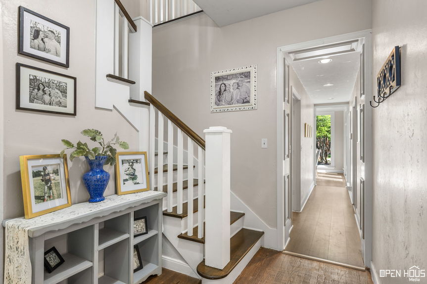 Hallway view with a staircase, framed pictures, and a welcoming console table.
