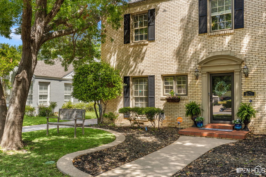 Close-up of the home's entrance with arched doorway, flanked by potted plants and a welcoming mat.