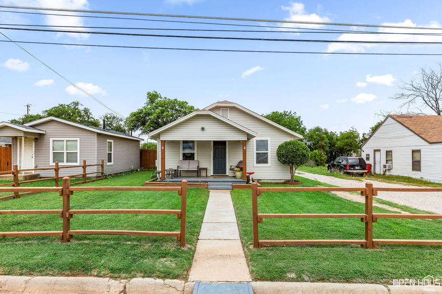 Exterior of a single-story house with a covered front porch and a lush green lawn.