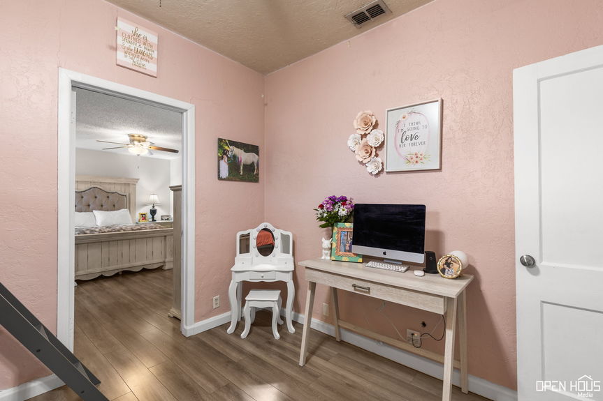 Room with two doors leading to the master bedroom and hallway, featuring a modern desk setup.