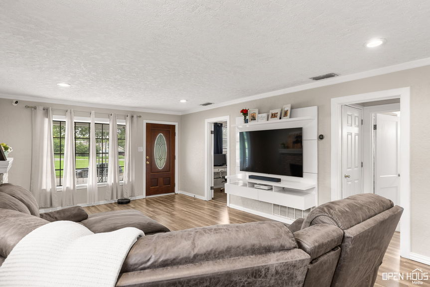Open and bright living room leading to the entryway, highlighted by natural light and an inviting layout.