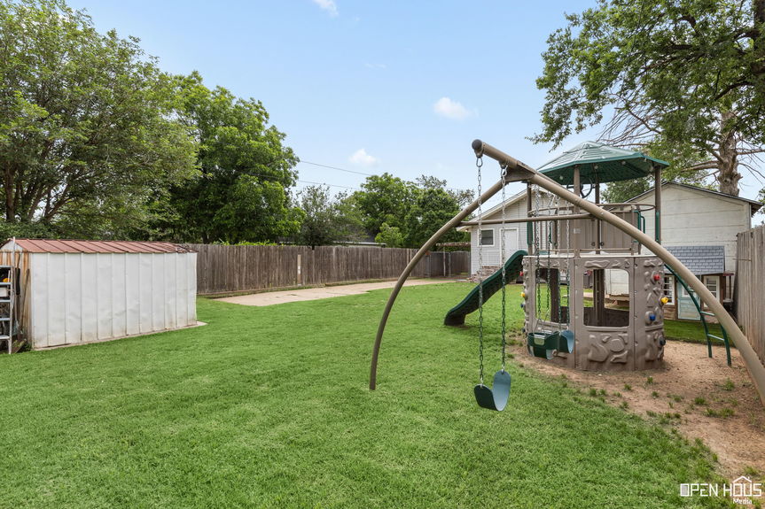 Rear view of a house with a small brick platform and expansive lawn area, suitable for entertainment.