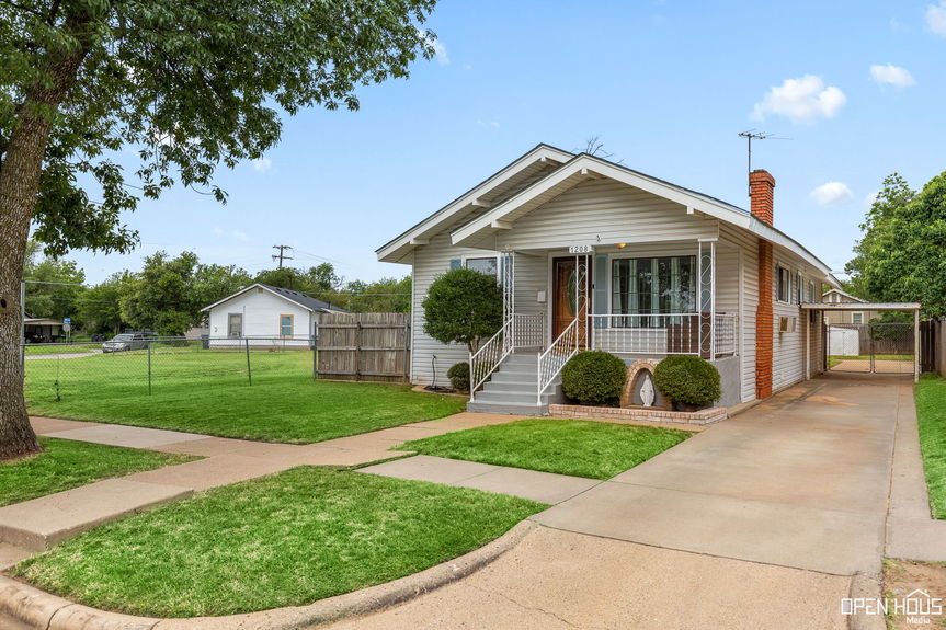 Exterior view of 1208 Tyler Ln showing a grassy yard and a gated driveway.