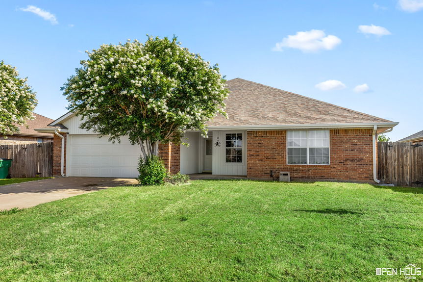 Exterior view of 910 E Texas Ave, featuring a brick and vinyl siding home with a well-maintained lawn and an attached 2-car garage.