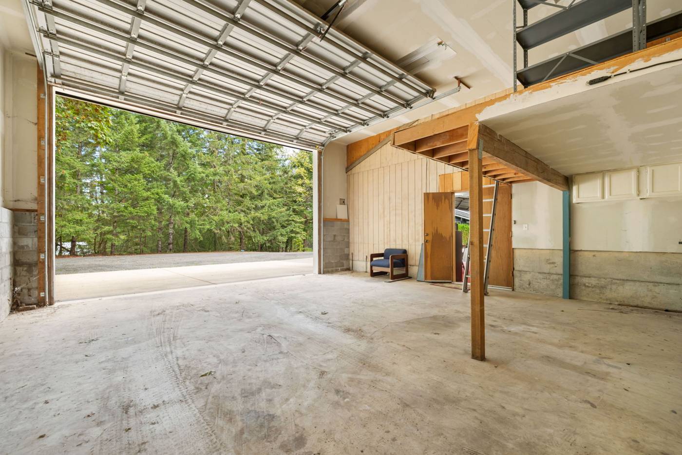 Large shop with overhead door open to the trees