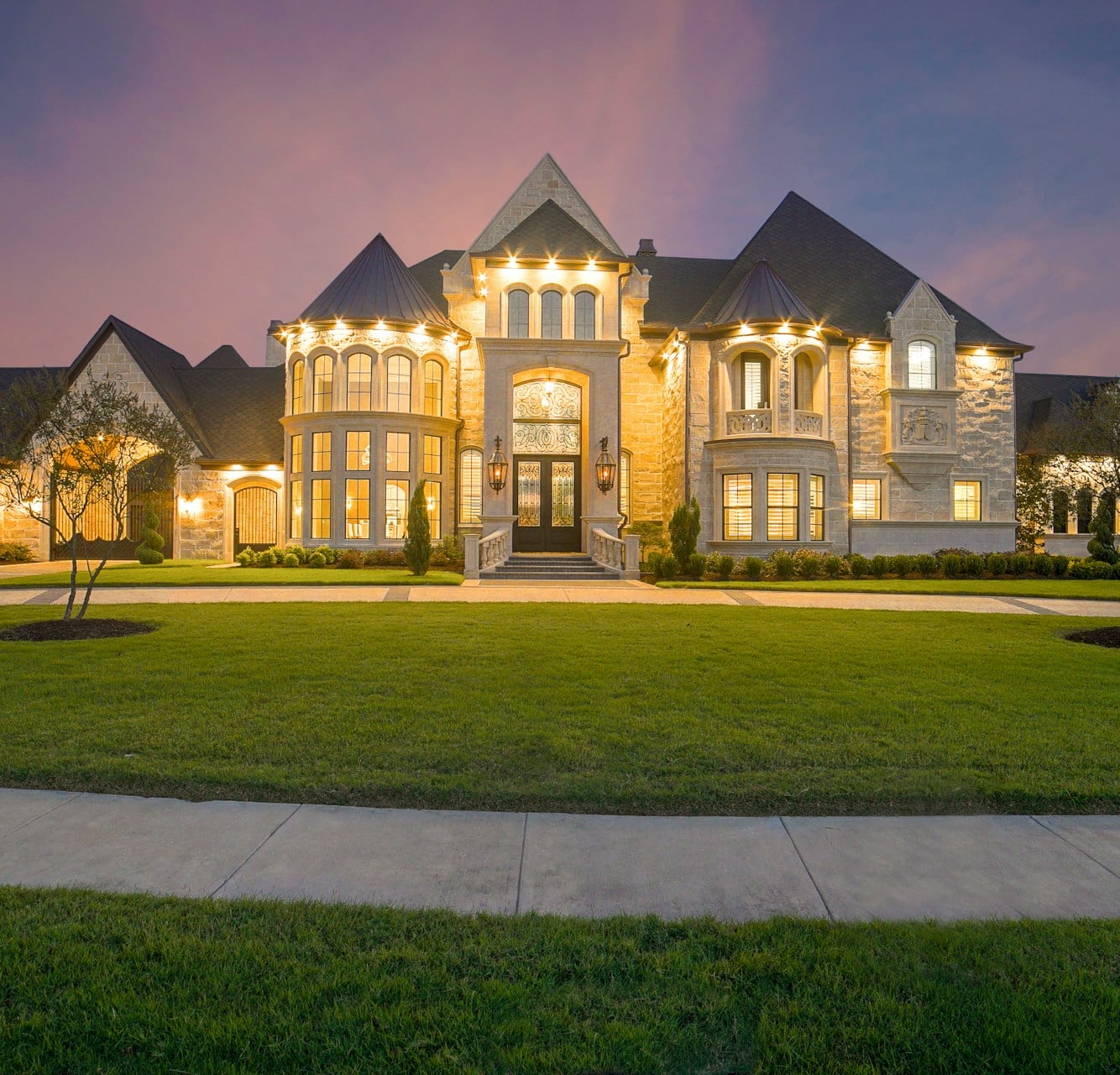 Large stone estate home lit at dusk representing million-dollar homes in North Pittsburgh