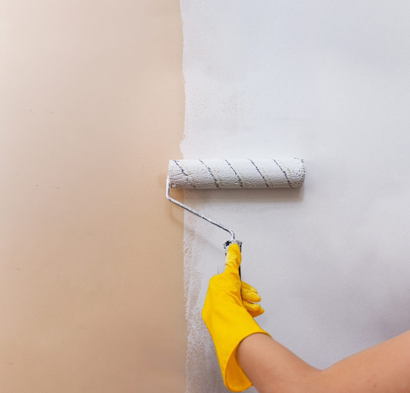 Paint roller applying fresh neutral paint to a wall before selling a North Hills home