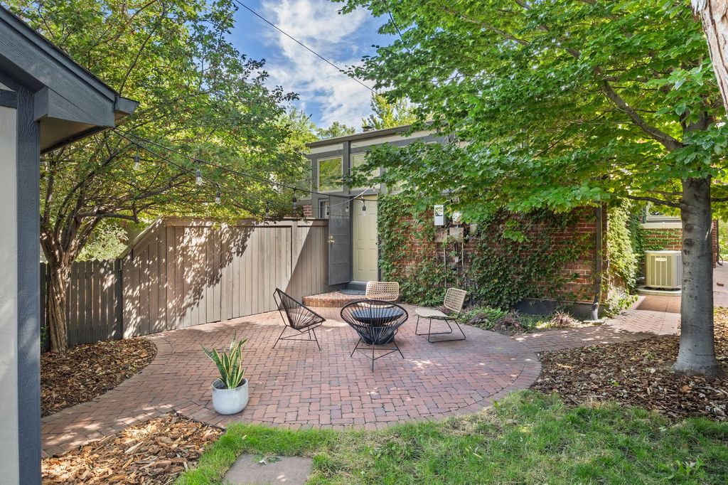 Brick patio and mature shade trees behind a Craftsman half-duplex in Alamo Placita, Denver