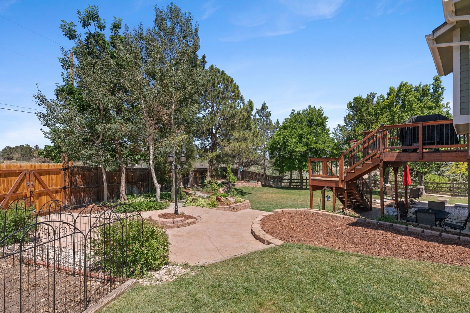 Fenced backyard with mature landscaping and deck backing to open space at 12221 W Prentice Pl in Littleton, Colorado