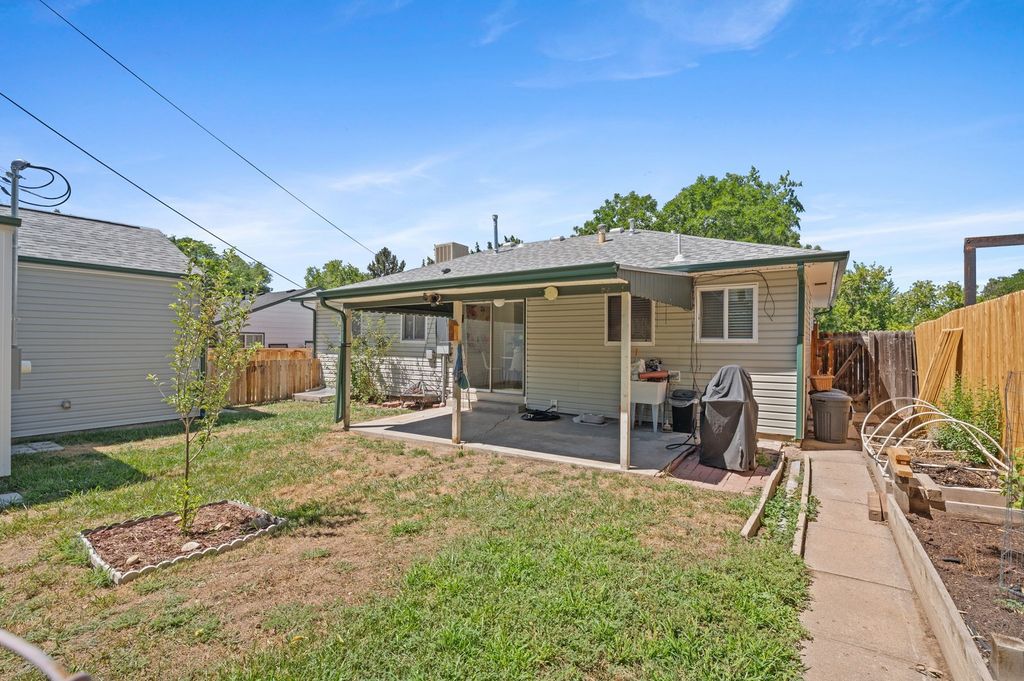 Fenced backyard with covered patio and raised garden beds at 2740 S Madison St, Wellshire, Denver