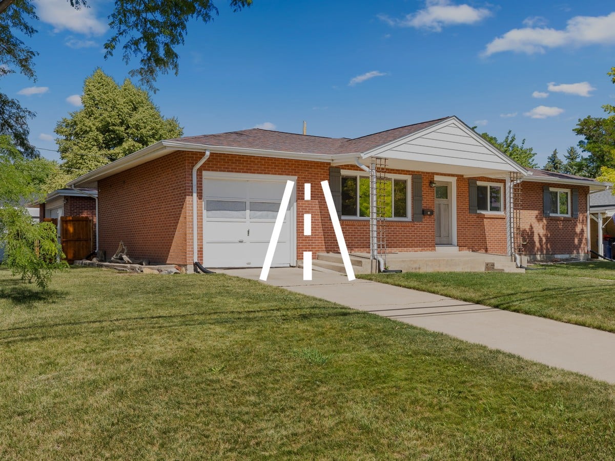 Brick ranch home with a single-car garage, front lawn and concrete walkway under a blue sky