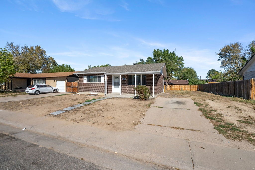 Brick ranch exterior and long driveway with RV parking at 5504 Sable St in Montbello, Denver