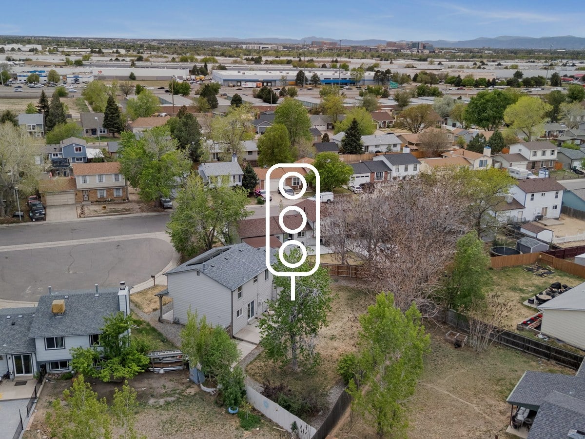 Aerial view of a suburban neighborhood with ranch and two-story homes, a curving street and mountains on the horizon