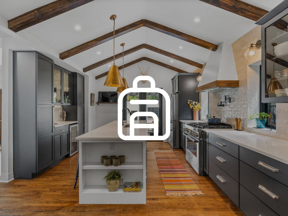 Kitchen with dark gray cabinets, a white island, brass pendant lights and exposed wood ceiling beams
