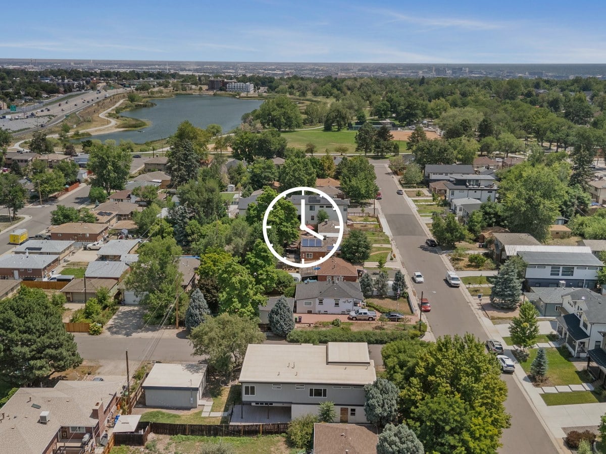 Aerial view of tree-lined residential streets with a lake, a park and a highway in the distance