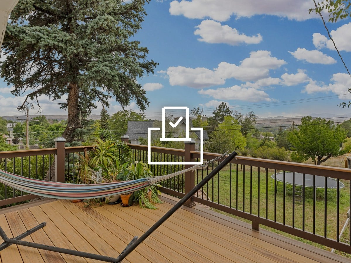Covered deck with a striped hammock and potted plants overlooking a backyard, trees and distant foothills