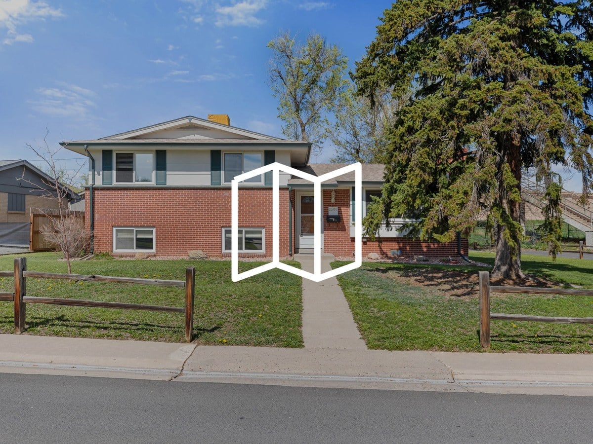 Two-story brick and siding home with a front lawn, split-rail fence and tall evergreen tree