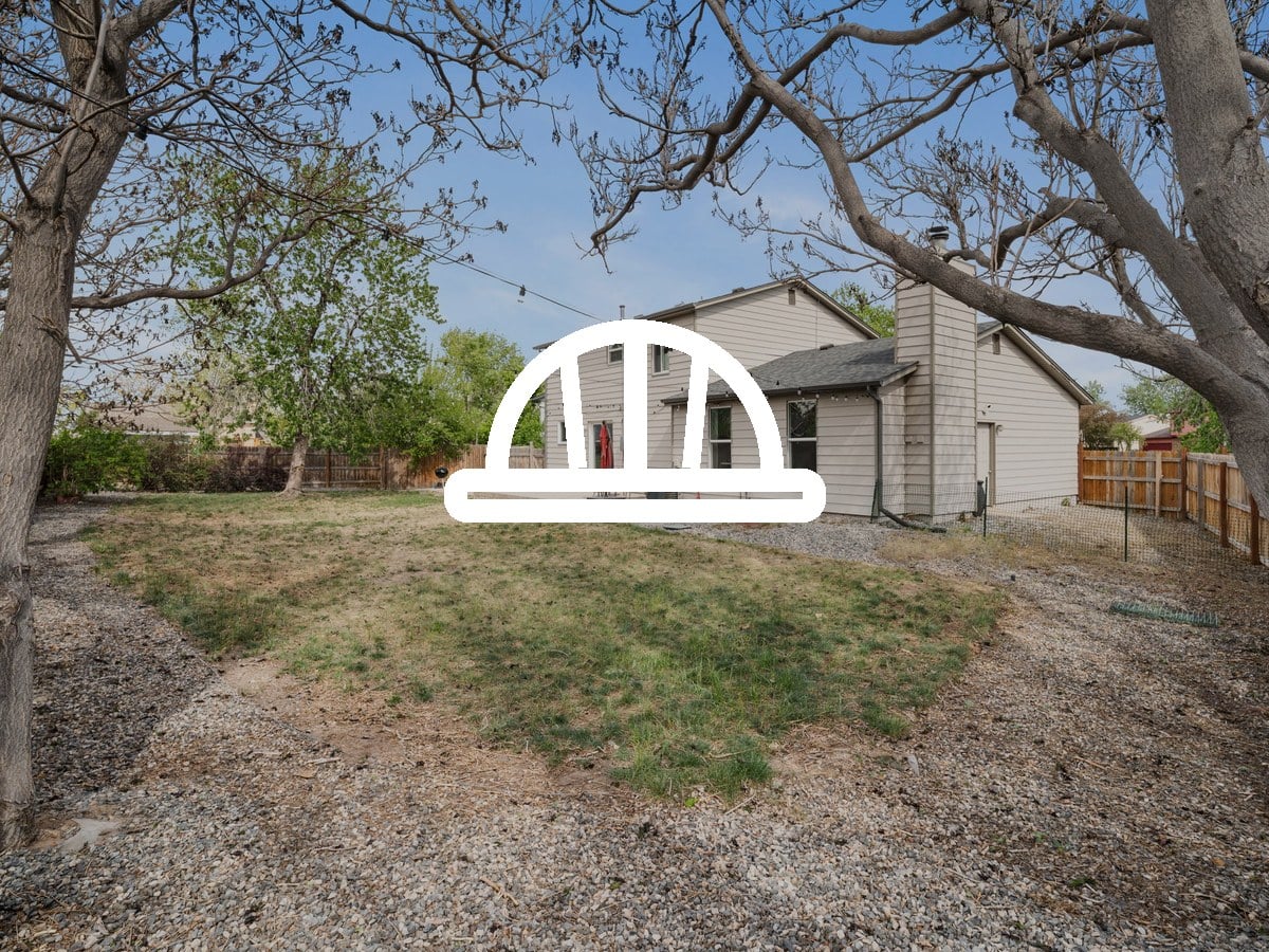 Backyard lawn and mature trees behind a two-story home