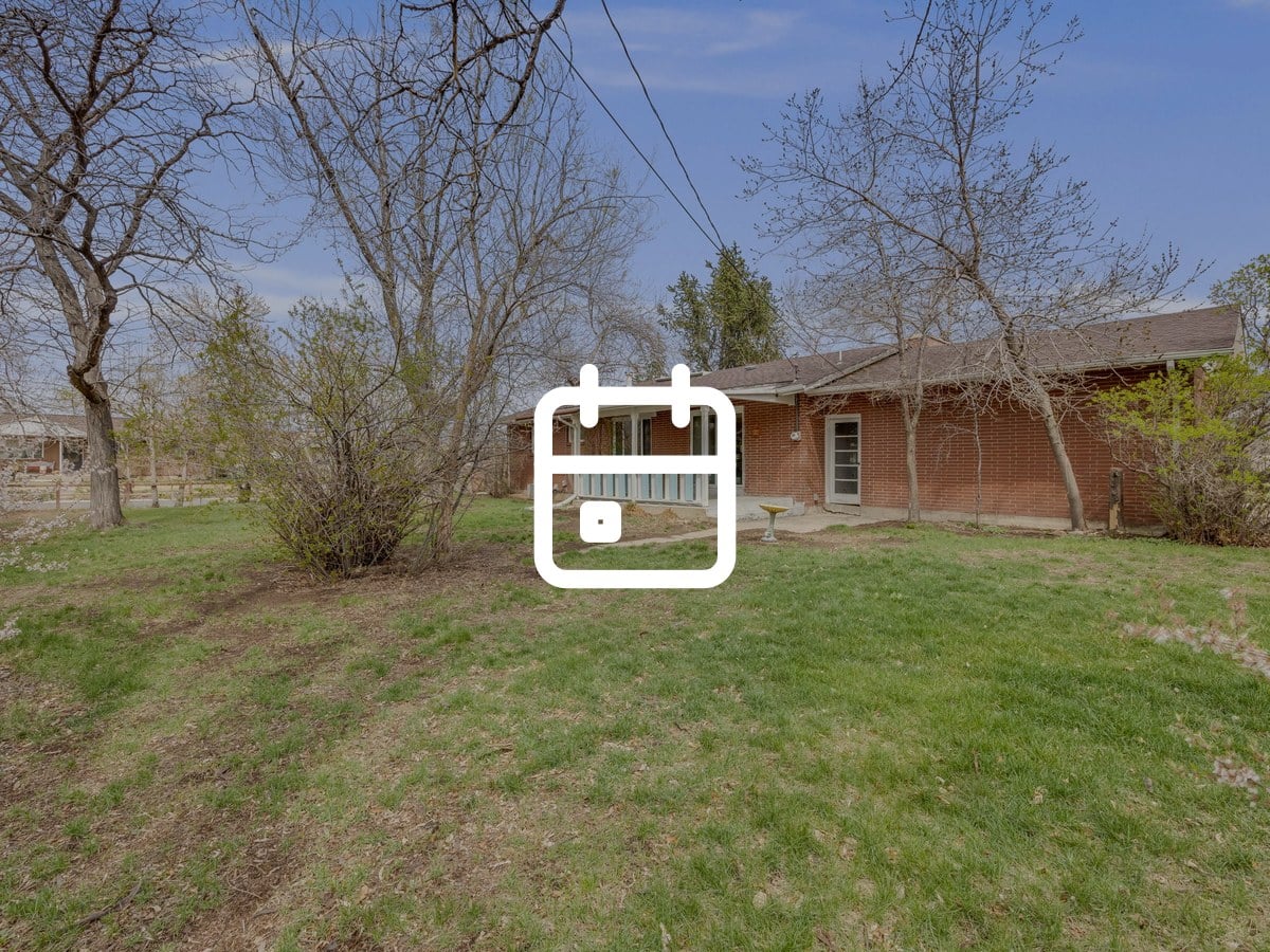 Long, low brick ranch home with a covered patio, a wide lawn and bare trees