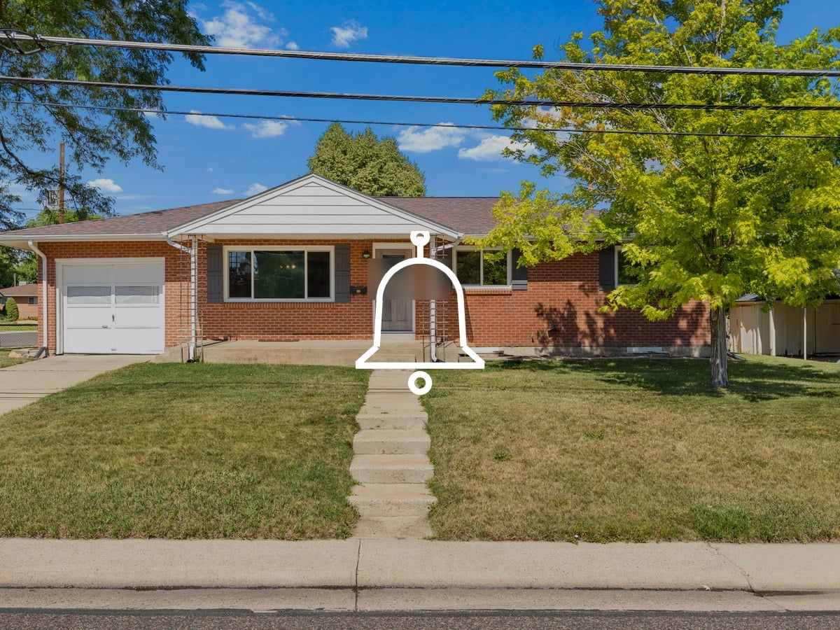 Single-story red brick ranch home with a white garage door, a front lawn and a concrete walkway under a blue sky