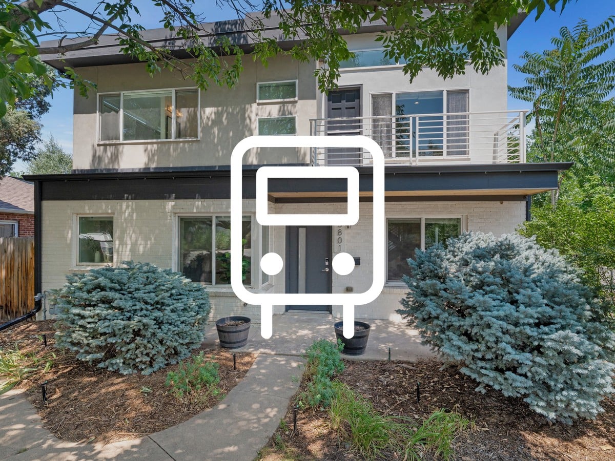 Two-story modern home with a white brick lower level, balcony and blue spruce shrubs