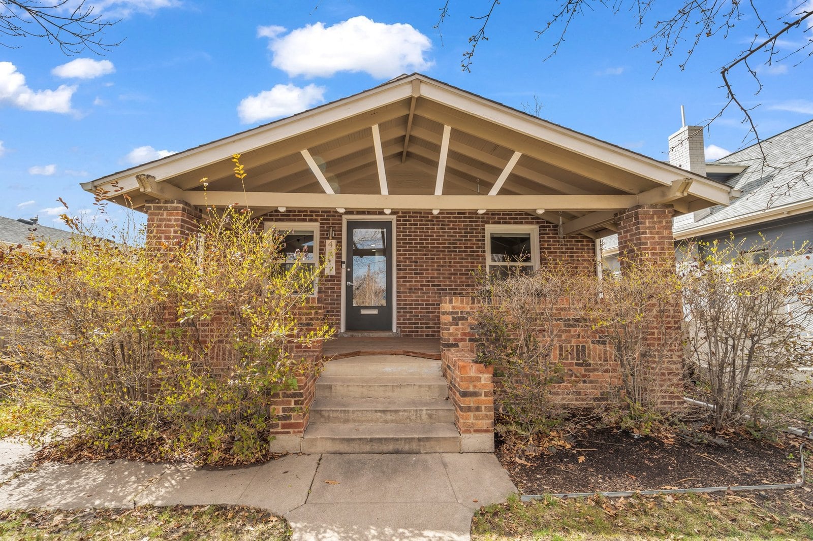 Craftsman bungalow with exposed rafter tails and a brick porch in northwest Denver