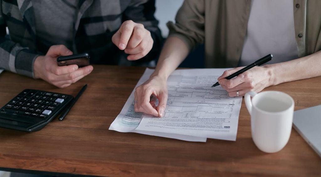 Close-up of hands using calculator and reviewing mortgage documents