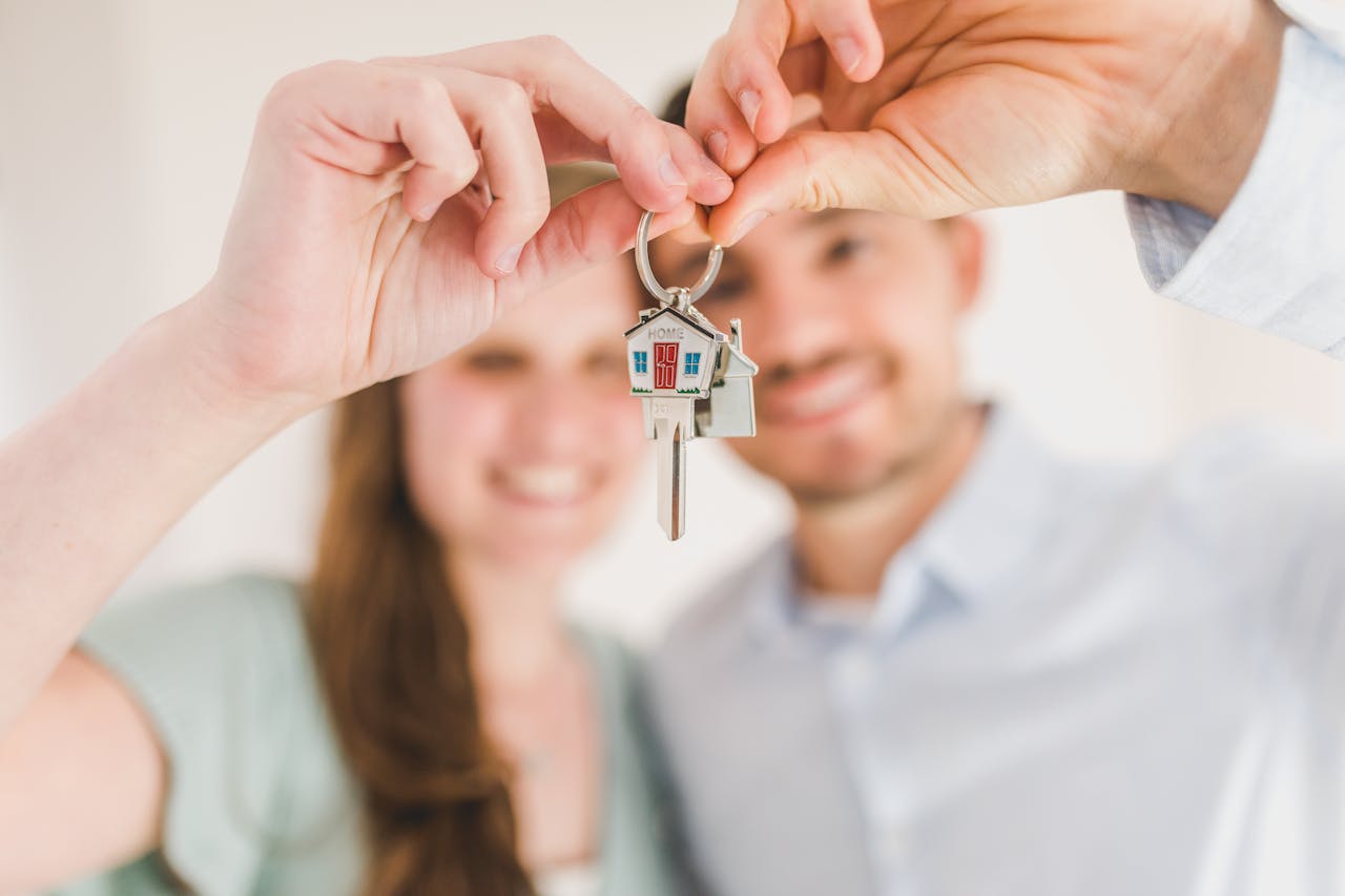 Smiling couple holding house keys outside their new Boston home