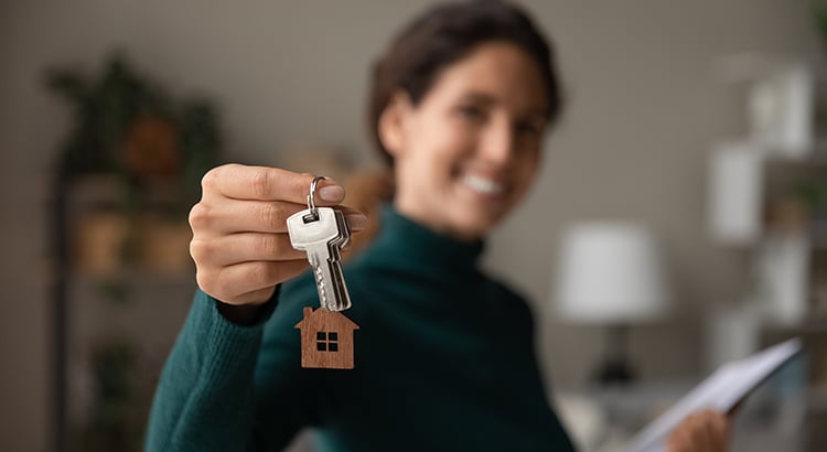 Close up focus on keys, smiling woman realtor selling apartment