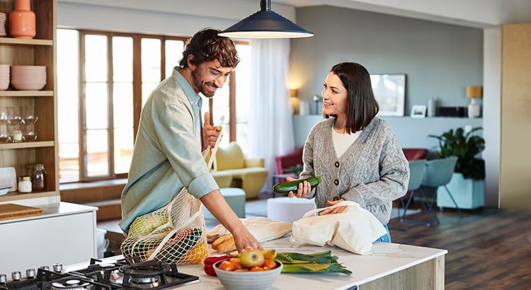 Smiling Couple Unpacking Vegetables In Kitchen