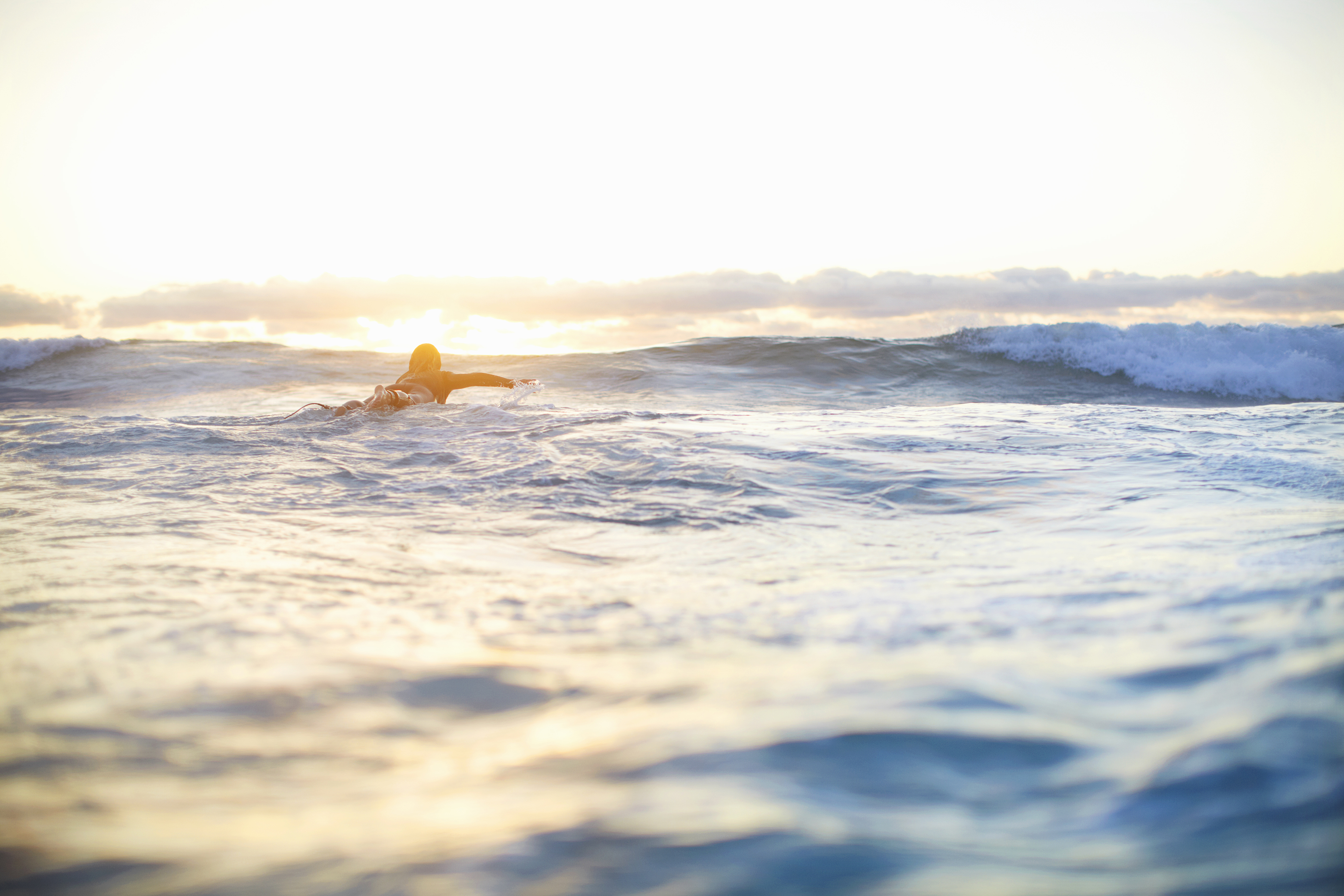 female-surfer-swimming-out-to-waves-on-surfboard-2024-10-18-17-27-13-utc