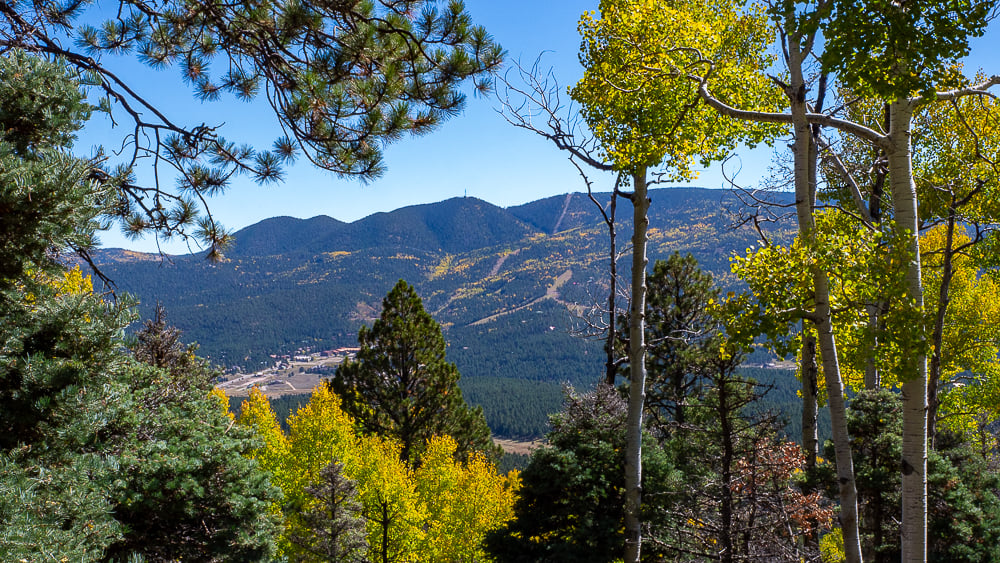 View of Angel Fire Resort’s ski hill on Agua Fria Peak framed by vibrant fall aspens and evergreen trees in Angel Fire, New Mexico.