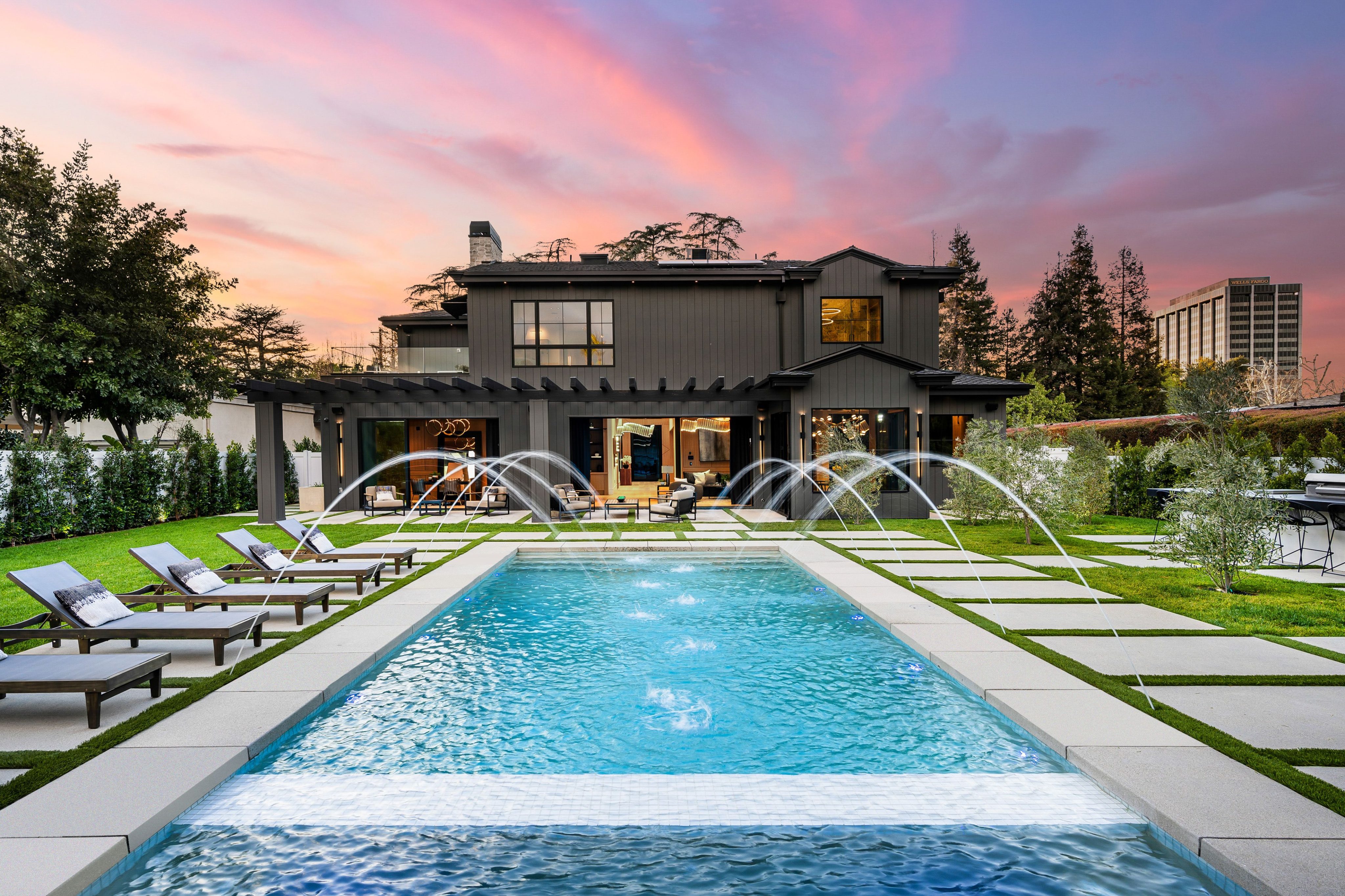 Modern luxury home with a swimming pool and sunset sky.