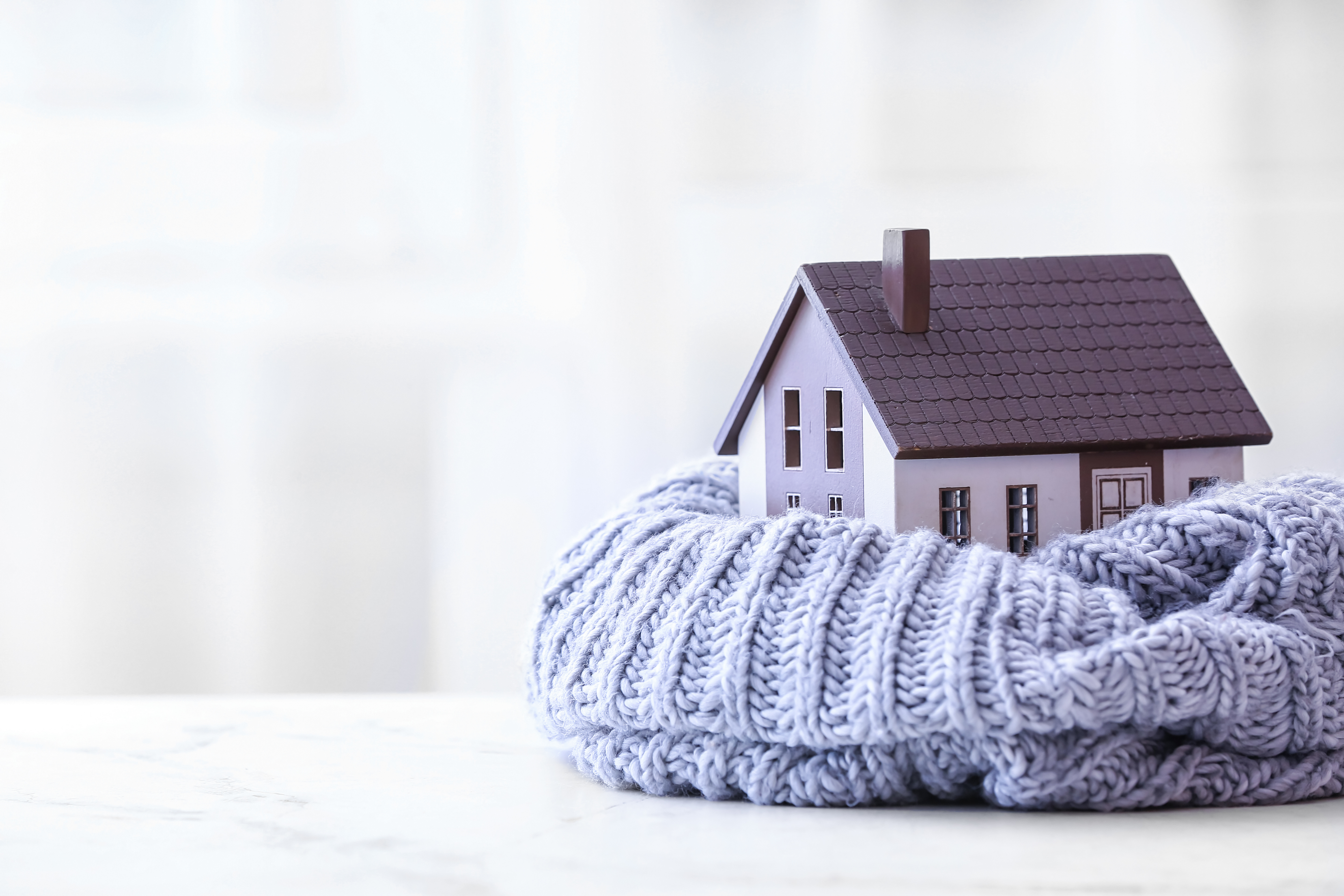 Figure of house and warm scarf on table. Concept of heating seas