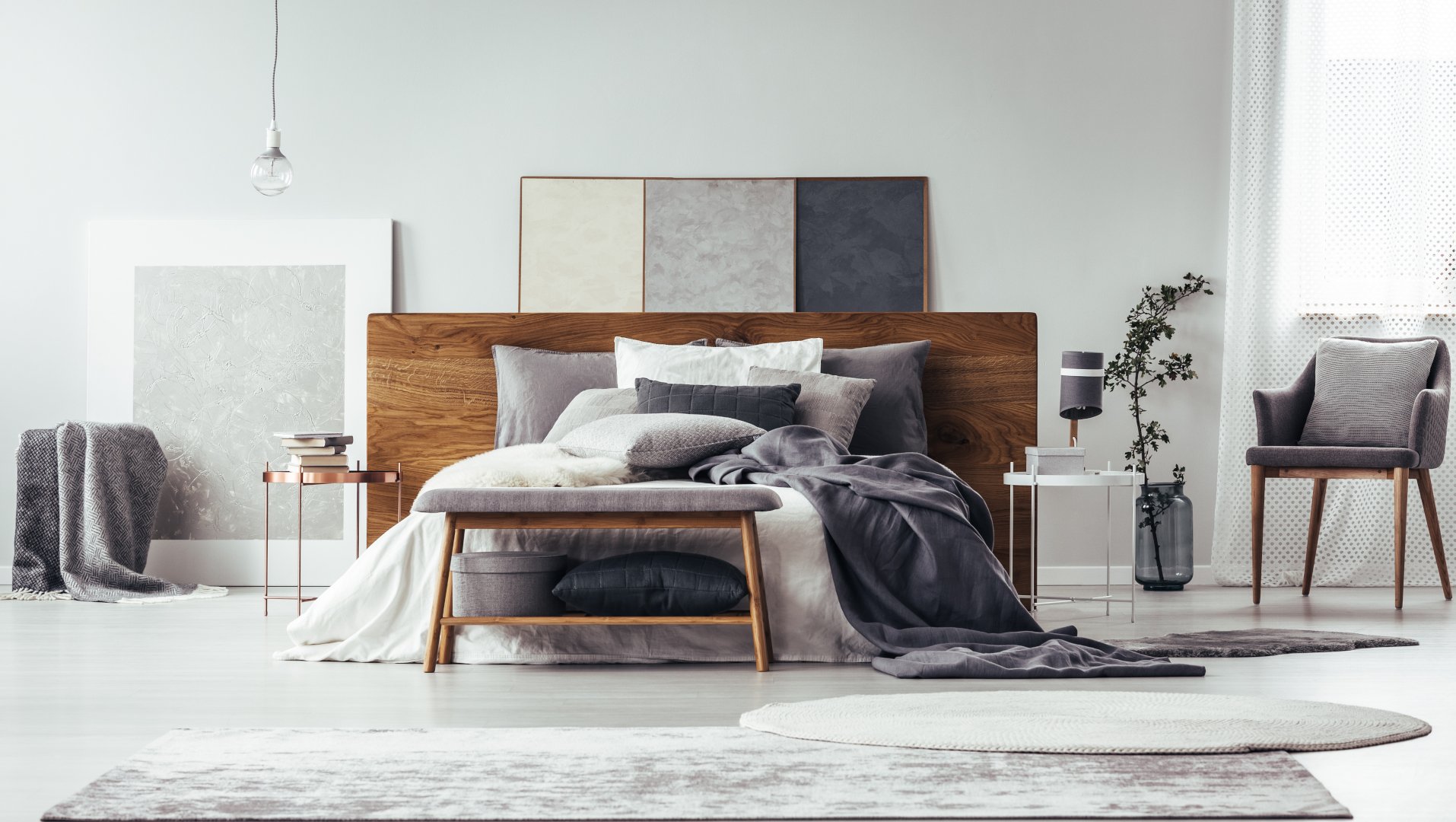grey bedroom interior with rugs, bench and chair