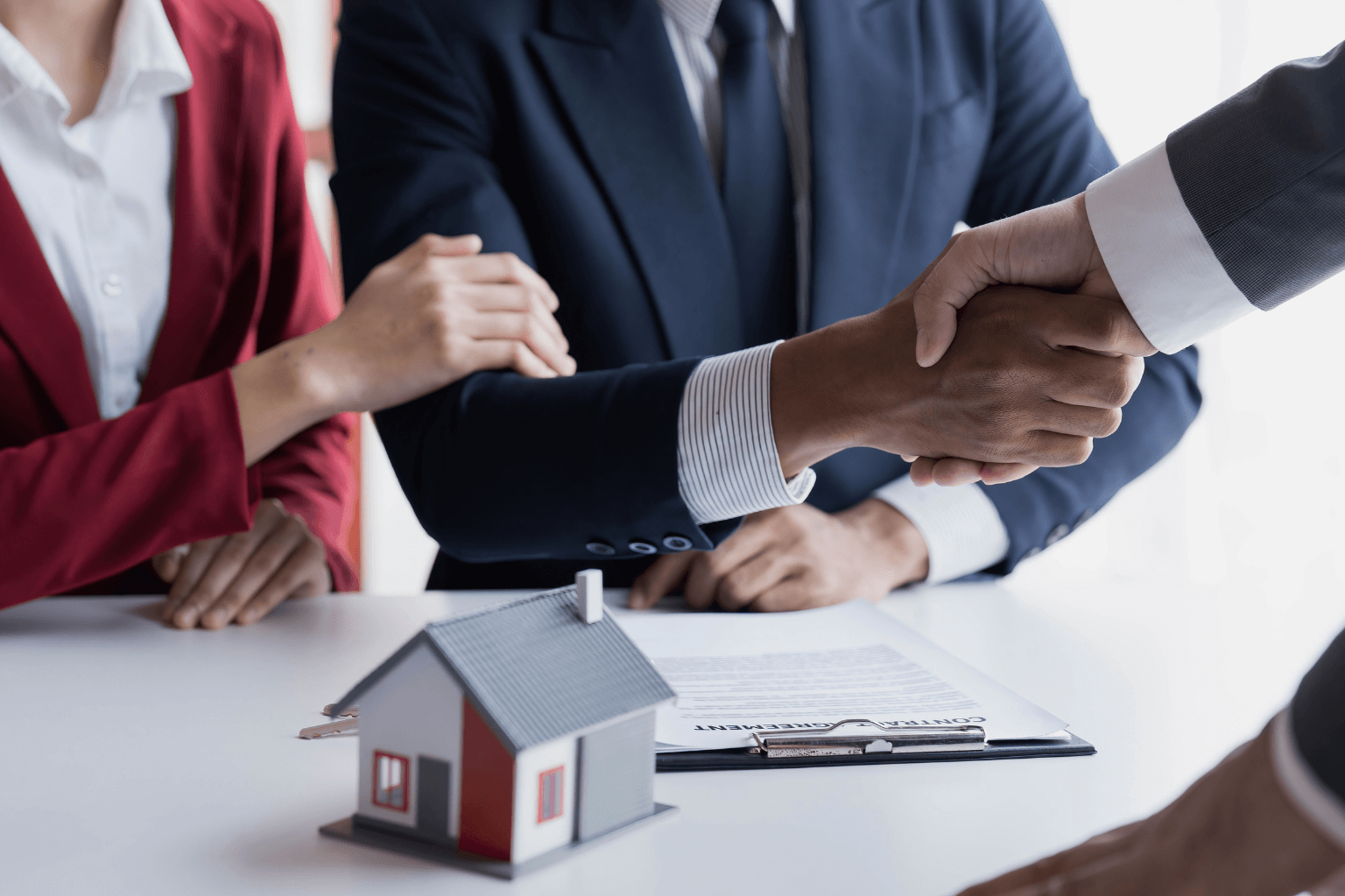 Real estate agent shaking hands with homebuyer at a table