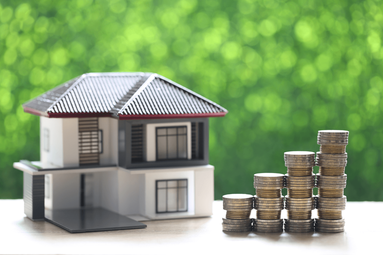 Stack of coins beside miniature house